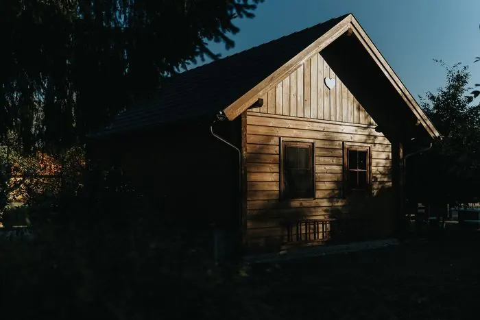 A Kiskunyhó gerendaháza esti fényben, a fák között