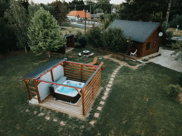 Pár a kerti jakuzziban, drónnal fotózva, háttérben a gerendaház