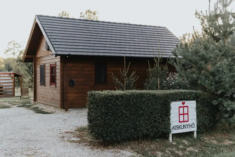 A Kiskunyhó táblája a bejáratnál, a sövény előtt