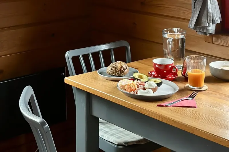 Terített reggeli az étkezőasztalon, piros pöttyös bögrével